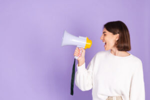 Mujer con jersey blanco hablando por megáfono estrategia de endomarketing